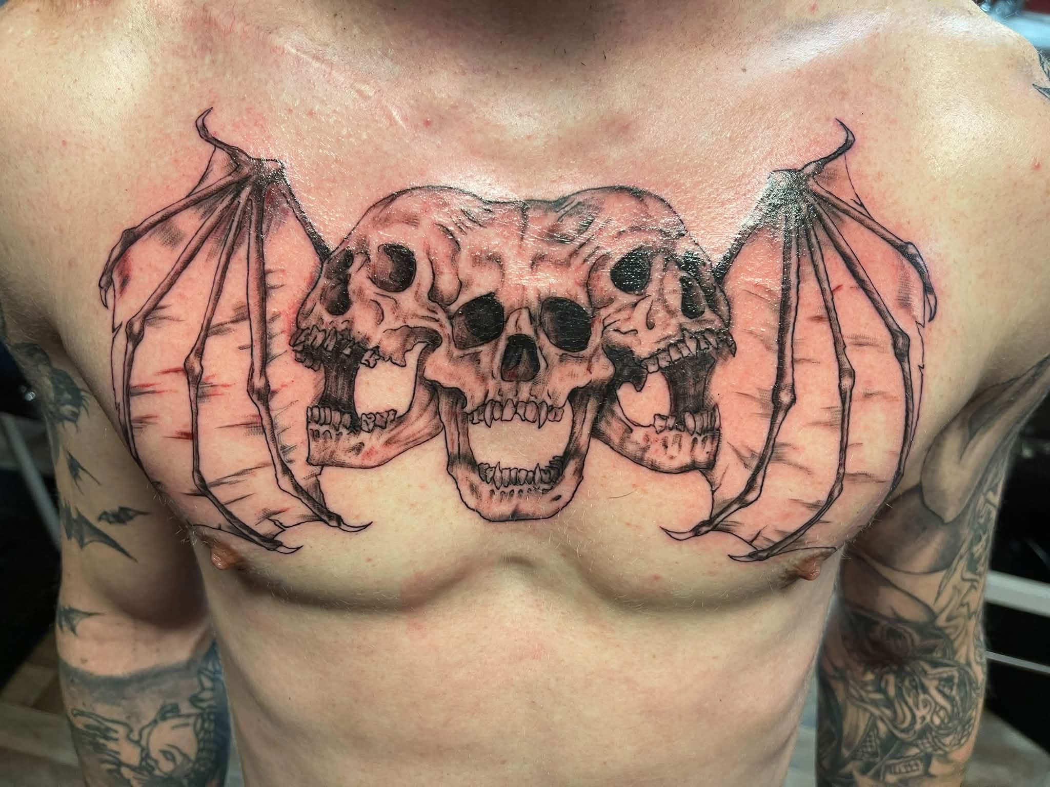 Three skulls with bat wings tattoo
